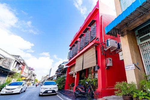 a red building on the side of a street with cars at Yu Cafe Hostel in Songkhla