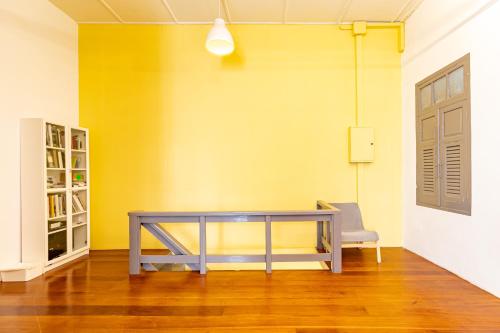 a dining room with a table and a yellow wall at Yu Cafe Hostel in Songkhla