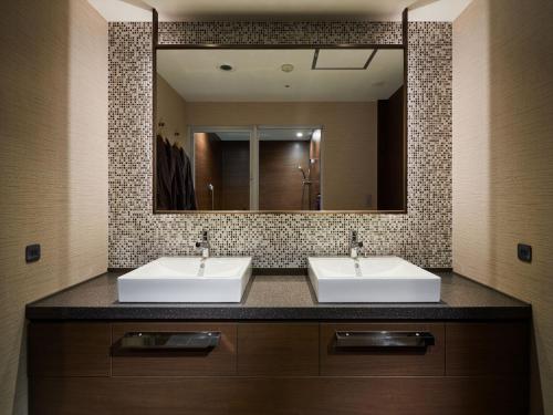 a bathroom with two sinks and a large mirror at Okinawa NaHaNa Hotel & Spa in Naha