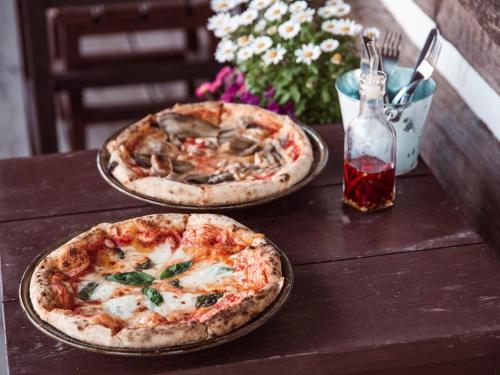 dos pizzas están sentadas en una mesa de madera en Margo's Garden Farmstay, Kiroro, en Akaigawa