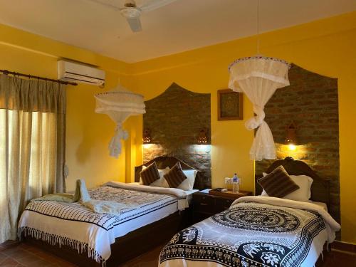 two beds in a room with yellow walls at Chautari Garden Resort in Sauraha