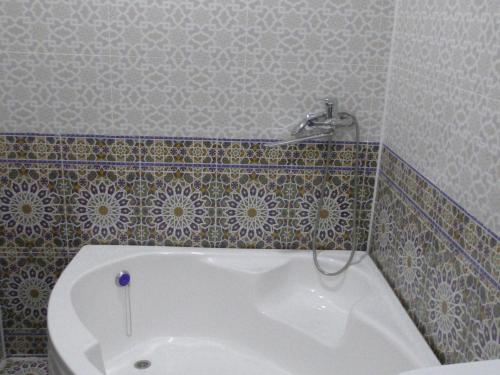 a bath tub in a bathroom with a tile wall at Khiva Ibrohim Guest House in Khiva