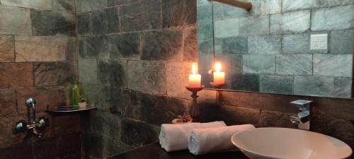 ein Badezimmer mit einer Kerze und einem Waschbecken mit Handtüchern in der Unterkunft Musafir cottage in Pālampur