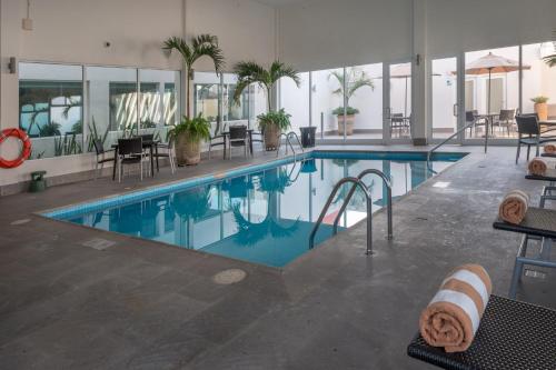 a swimming pool in a hotel with chairs and tables at Holiday Inn Express & Suites Silao Aeropuerto Terminal by IHG in Silao