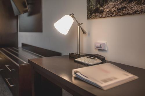 a desk with a lamp and a book and a phone at Holiday Inn Express & Suites Silao Aeropuerto Terminal by IHG in Silao