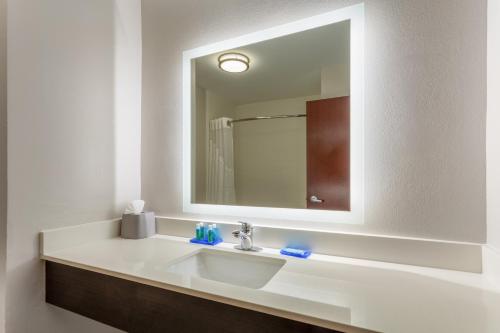La salle de bains est pourvue d'un lavabo blanc et d'un miroir. dans l'établissement Holiday Inn Express Arrowood, an IHG Hotel, à Charlotte