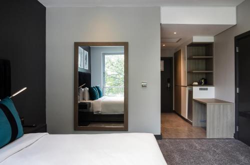 a bedroom with a white bed and a mirror at The Capital Empire in Johannesburg