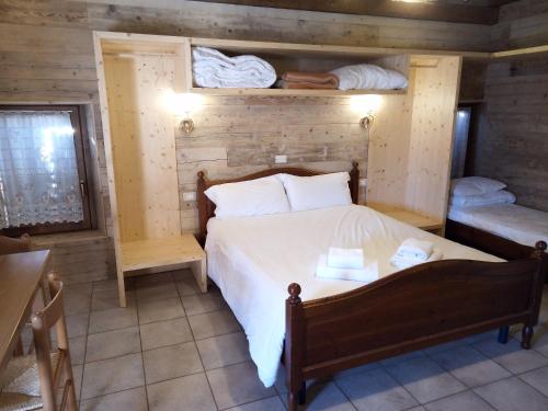 ein Schlafzimmer mit einem Bett mit einer Holzwand in der Unterkunft Agriturismo Cornolade in Ponte nellʼAlpi