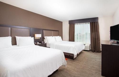 a hotel room with two beds and a flat screen tv at Holiday Inn Express Hotel & Suites Glasgow by IHG in Glasgow