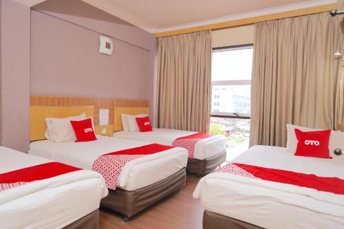 a hotel room with three beds with red pillows at Houz Inn in Bintulu