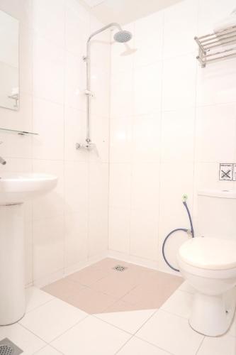 a white bathroom with a shower and a toilet at Houz Inn in Bintulu