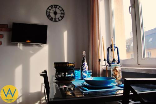 a dining room table with a clock on the wall at Apartamenty Wójcik Loft in Gdynia