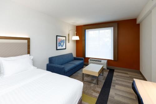 une chambre d'hôtel avec un lit et un canapé bleu dans l'établissement Holiday Inn Express & Suites - Sturbridge, an IHG Hotel, à Sturbridge