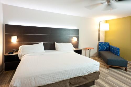 a bedroom with a large bed and a blue chair at Holiday Inn Express Hotel & Suites Scott-Lafayette West by IHG in Scott