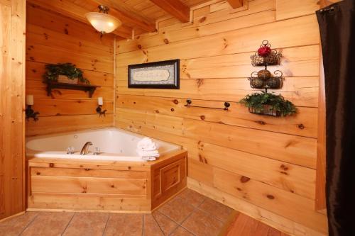 een badkamer met een bad en een houten muur bij Amazing Grace in Sevierville