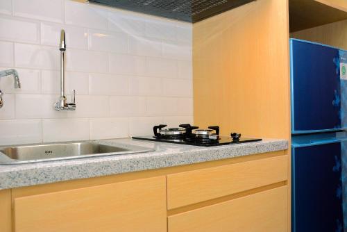 a kitchen with a stove and a sink at Minimalist and Homey 1BR Grand Kamala Lagoon Apartment By Travelio in Bekasi