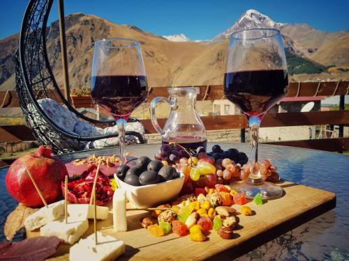 two glasses of wine sitting on a table with food at Sunshine Kazbegi in Stepantsminda