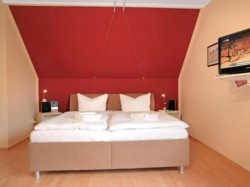 um quarto com uma cama com uma parede vermelha em Ferienwohnungen Am Lotsenstieg Morgensonne em Timmendorf