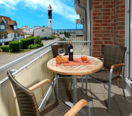 a table with a bottle of wine and glasses on a balcony at Haus Südwester Strandschnecke in Timmendorf