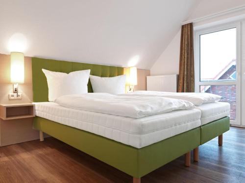 a bedroom with a large bed with a green headboard at Haus Südwester Strandschnecke in Timmendorf