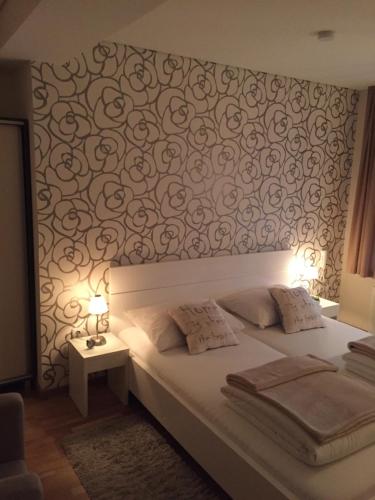 a bedroom with a bed and a wall with a flower pattern at B&B Alex18 in Niš