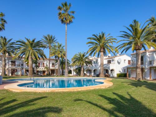 a pool with palm trees in front of houses at Holiday Home La Aldea by Interhome in Denia