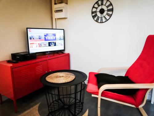 un salon avec une chaise rouge et une télé dans l'établissement Studio Gare, à Rouen