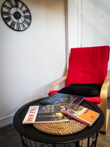 une table avec des livres, une chaise rouge et une horloge dans l'établissement Studio Gare, à Rouen
