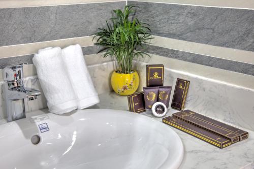 a bathroom sink with a plant in a yellow vase at The Flamboyant #StayWork Vinhomes Imperia in Hai Phong