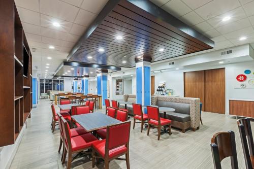 a restaurant with red chairs and tables and a bar at Holiday Inn Express & Suites - Coffeyville by IHG in Coffeyville