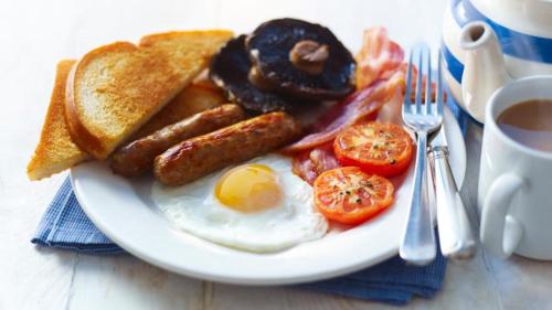 a plate of breakfast food with eggs bacon tomatoes and toast at Moba Hotel & Convention Centre in Kitwe