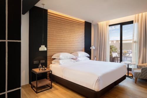 een slaapkamer met een groot wit bed en een stoel bij Casa Elliot by Bondia Hotel Group in Barcelona