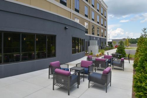 a patio with purple chairs and tables outside of a building at Holiday Inn Express and Suites Bryant - Benton Area by IHG in Bryant