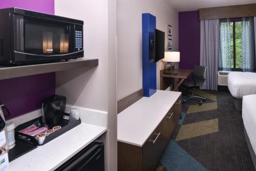 a hotel room with a bed and a desk with a microwave at Holiday Inn Express and Suites Bryant - Benton Area by IHG in Bryant