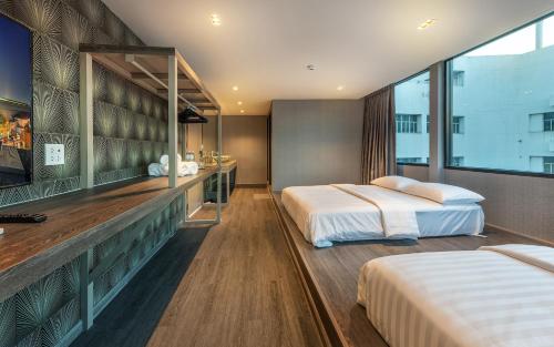 two beds in a hotel room with a large window at Happy Station Bangkok in Bangkok