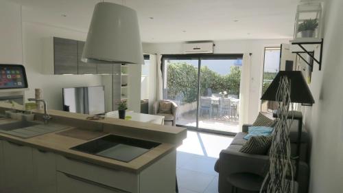 Il dispose d'une cuisine avec un évier et d'un salon avec un canapé. dans l'établissement Sol-y-Days California, Superbe appartement rénové en RDC avec Parking, belle terrasse ombragée, à 200m de la plage, au Grau-du-Roi