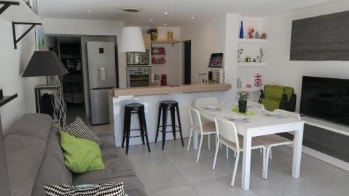 une cuisine et un salon avec une table et des chaises blanches dans l'établissement Sol-y-Days California, Superbe appartement rénové en RDC avec Parking, belle terrasse ombragée, à 200m de la plage, au Grau-du-Roi