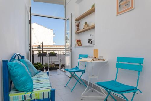 Pokój z niebieskimi krzesłami i biurkiem na balkonie. w obiekcie Andriani Apartment w mieście Zakintos