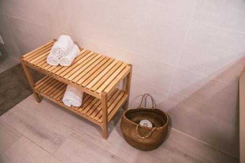 a bathroom with a bench with towels and a basket at Marlin House in Baleal