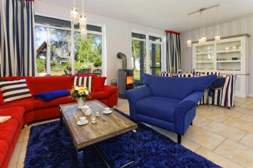 a living room with red and blue chairs and a table at Lotsenstieg 03 in Ostseebad Karlshagen