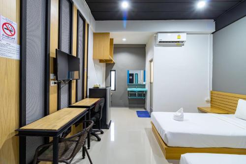 a hotel room with two beds and a desk at CS Klongtoey Grand Resort in Ban Yep Chaeng