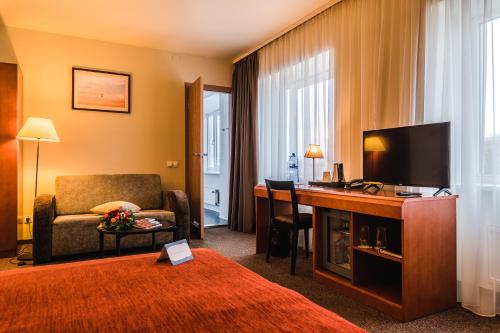 a hotel room with a bed and a desk with a television at Liva Hotel in Liepāja