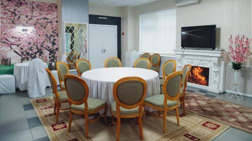 a dining room with a table and chairs and a fireplace at Aktobe Hotel in Aktobe