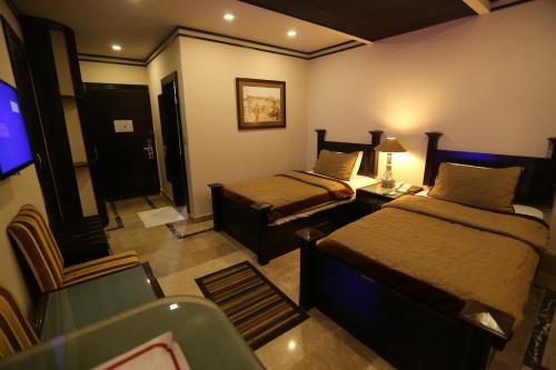 a hotel room with two beds and a television at City Centre Suites in Multan