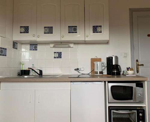 a kitchen with white cabinets and a microwave at Château d'Avanton in Avanton