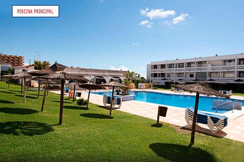 a resort with a pool with umbrellas and a building at Apartamento con vistas al mar primera linea playa Matalascañas in Matalascañas