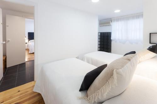 a white bedroom with two beds and a mirror at AG GERMANIAS CIUDAD in Gandía