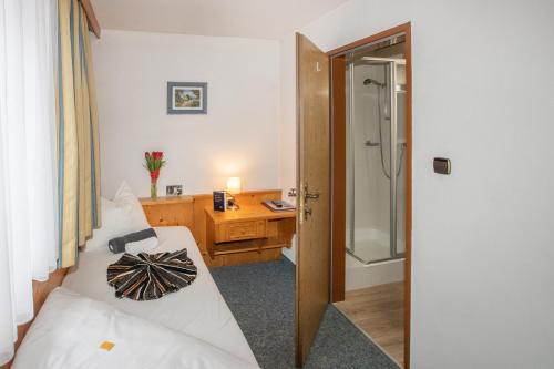 a bedroom with a bed and a desk and a shower at Hotel Untermetzger in Zell am Ziller