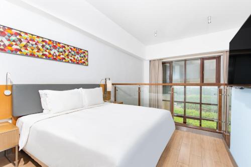 a white bedroom with a large bed and a window at Holiday Inn Express Haikou West Coast by IHG in Haikou