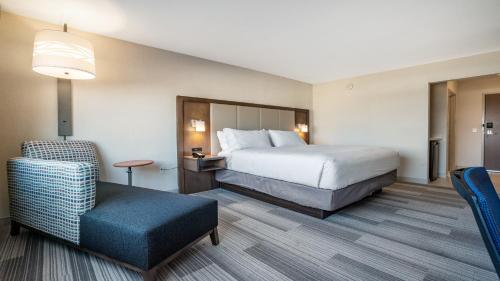 a hotel room with a bed and a chair at Holiday Inn Express & Suites Platteville by IHG in Platteville